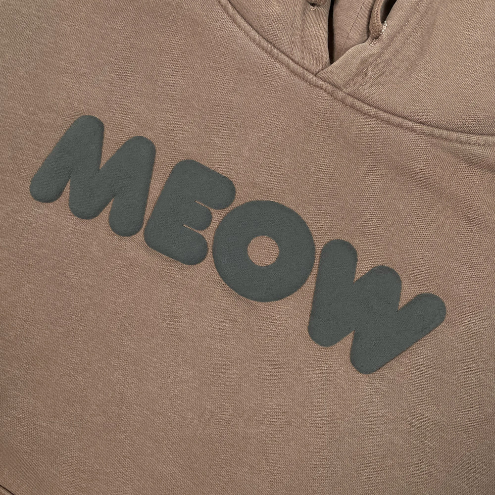 Close up of a brown sweatshirt with black lettering reading "MEOW"